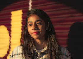 Portrait of a pensive teenager with sunlight casting vibrant shadows.