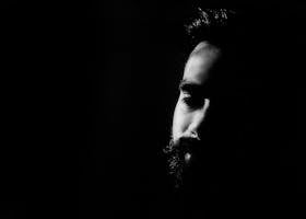 Captivating black and white portrait highlighting a man's thoughtful expression in deep shadows.